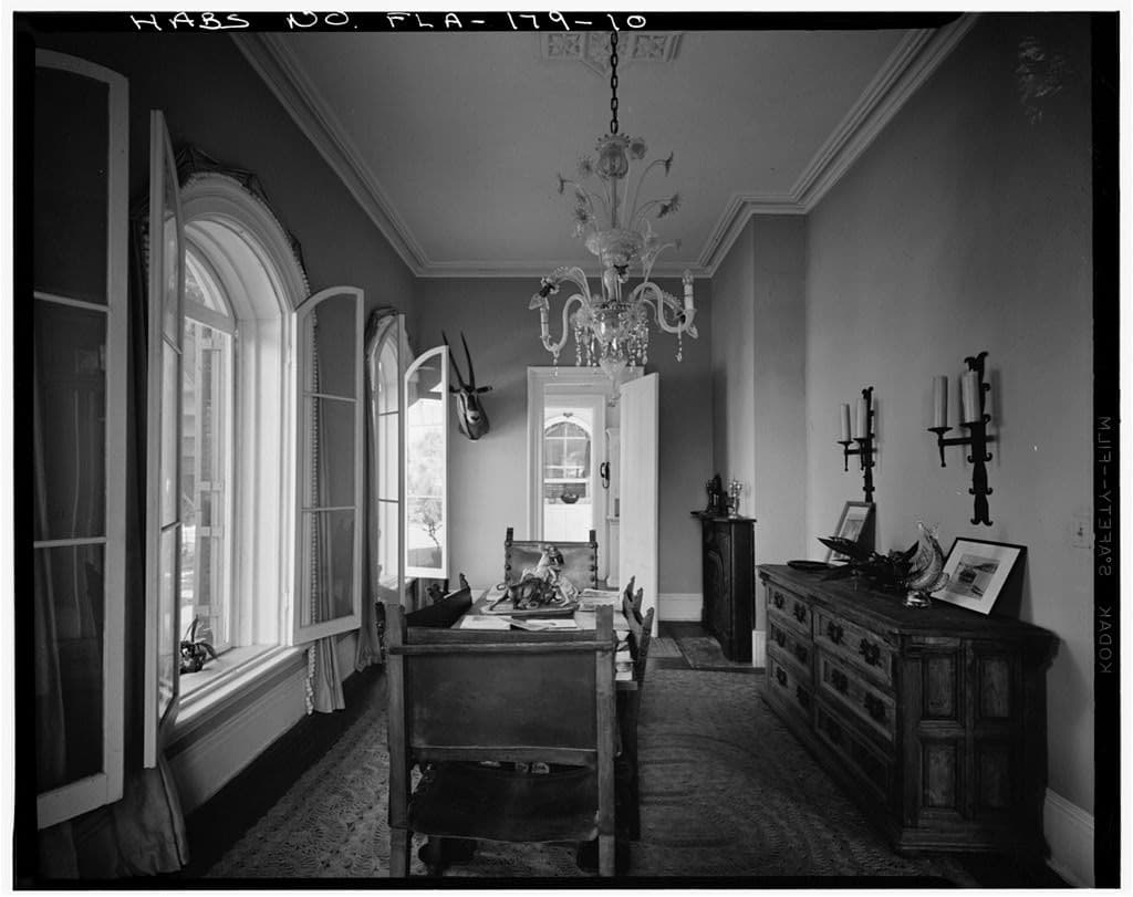 Black-and-white 1967 photograph of the Hemingway House dining room with arched windows, chandelier, long table and sideboard