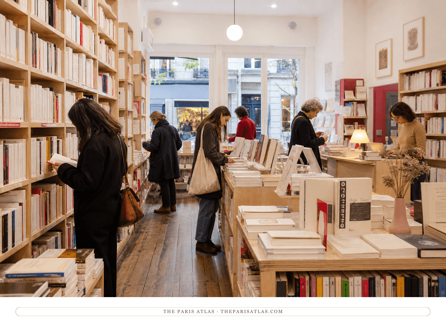 Readers browsing pale wooden shelves inside the Librairie des Femmes