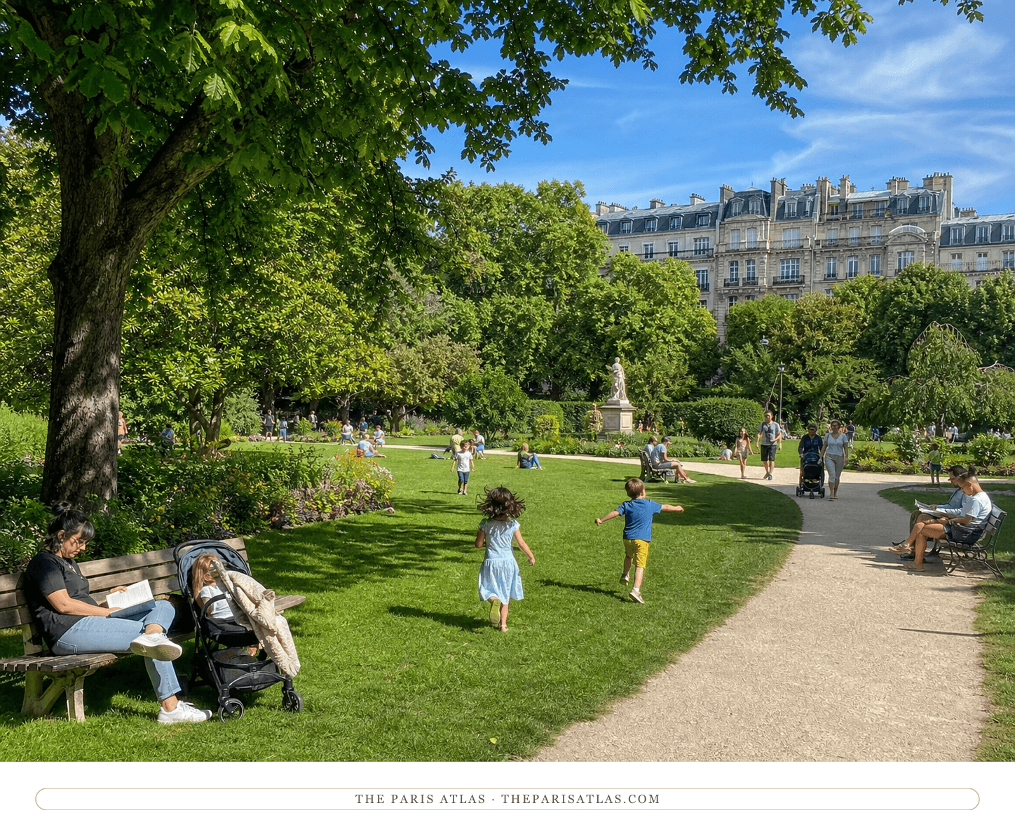 Families and children relaxing on a sunny lawn among trees and statuary in Parc Monceau