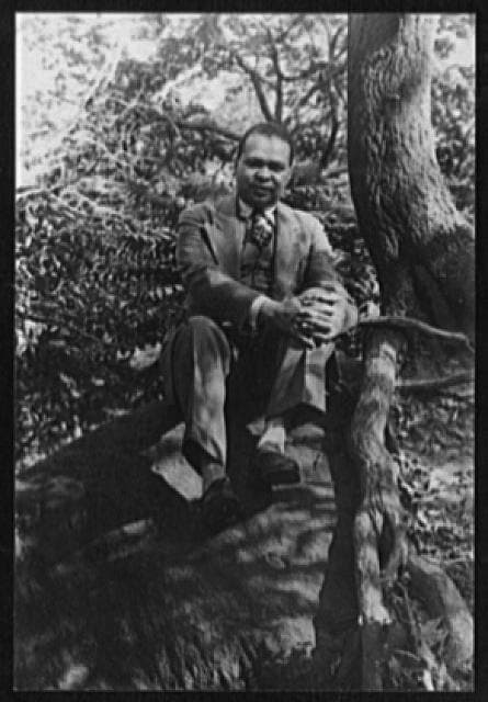 Countee Cullen photographed in profile in Central Park in 1941, wearing a dark suit and looking to his right