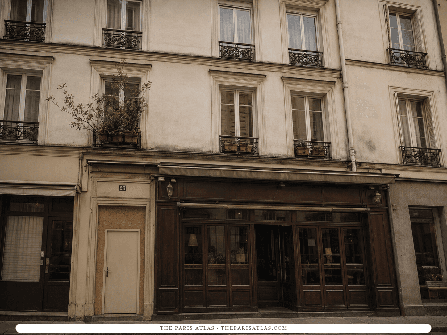 Reconstruction of 26 rue Saint-Benoît as it might have looked in the early 1950s — a narrow pale doorway marked 26 beside a dark wooden café front, iron balconies above