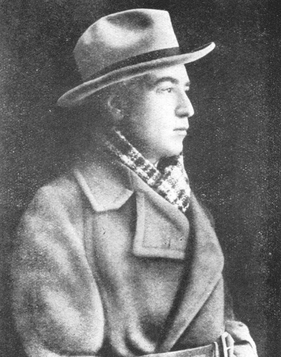 Abel Gance in 1924 in profile, wearing a fedora and heavy overcoat with a checked scarf