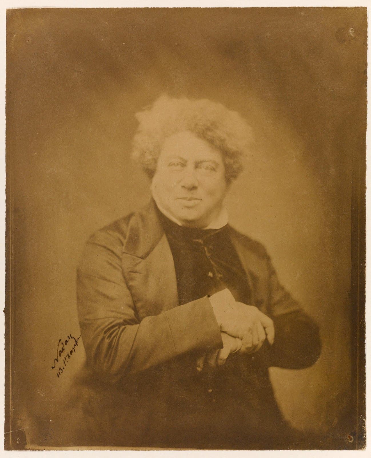 Alexandre Dumas seated in a dark coat, looking directly at Nadar's camera in a portrait made between 1853 and 1860