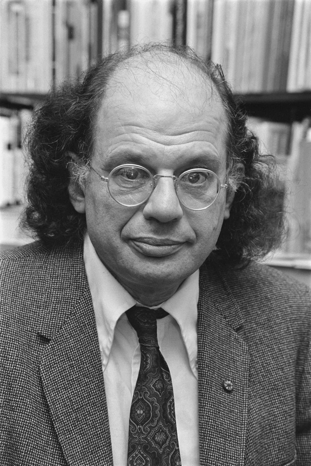 Allen Ginsberg seated at a table signing books for a queue of readers