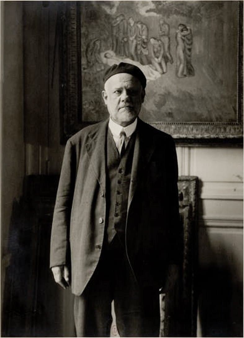 Ambroise Vollard in a cap, standing in his gallery beneath Picasso's Evocation (The Burial of Casagemas).