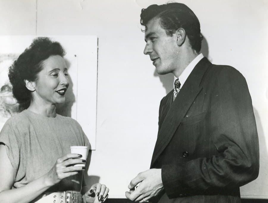 Anaïs Nin laughing with a paper cup in her hand, talking to the publisher George Leite at his Berkeley bookstore in 1946