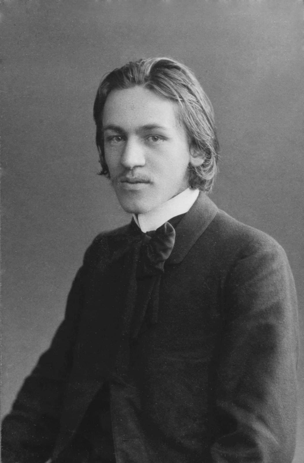 Blaise Cendrars at about twenty, in a dark coat and loosely knotted bow, in a studio portrait.