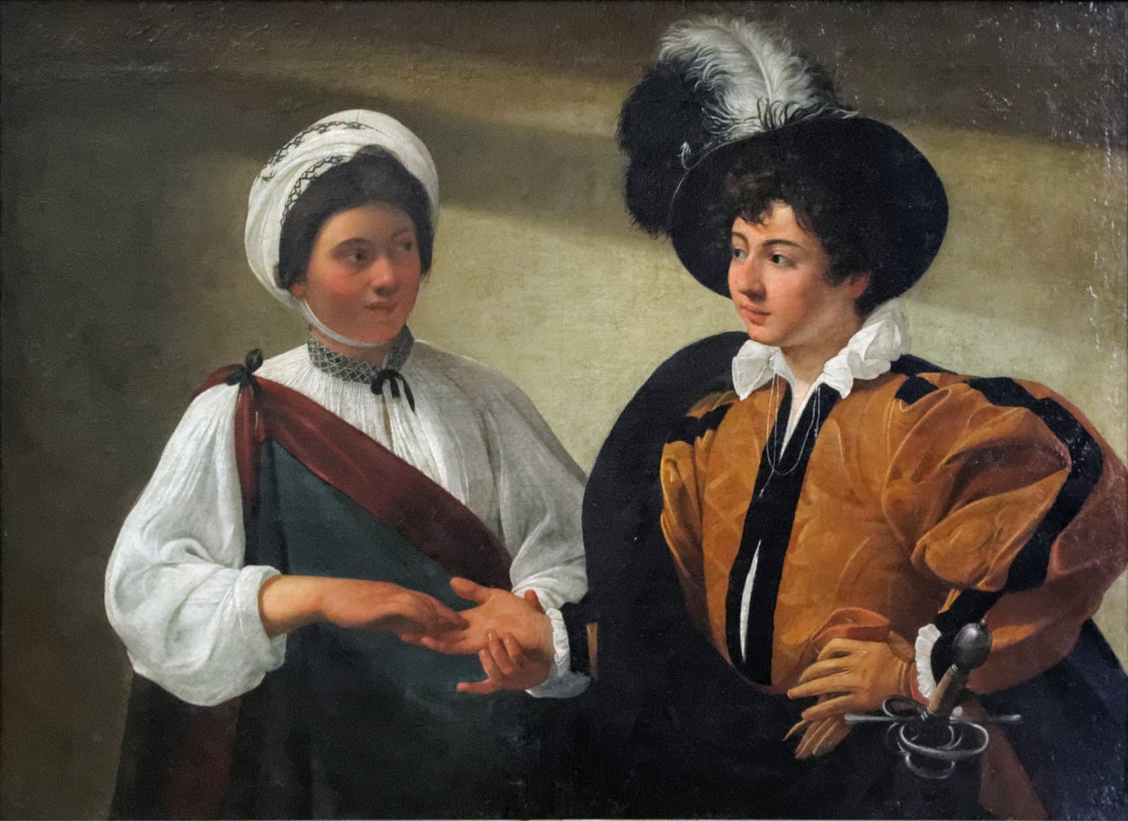 A young woman in a white blouse and turban holds the open right hand of a richly dressed boy in a plumed black hat and gold doublet, tracing his palm while she watches his face. Her fingers are closing on the ring on his finger. He looks back at her, one gloved hand resting on the hilt of his sword