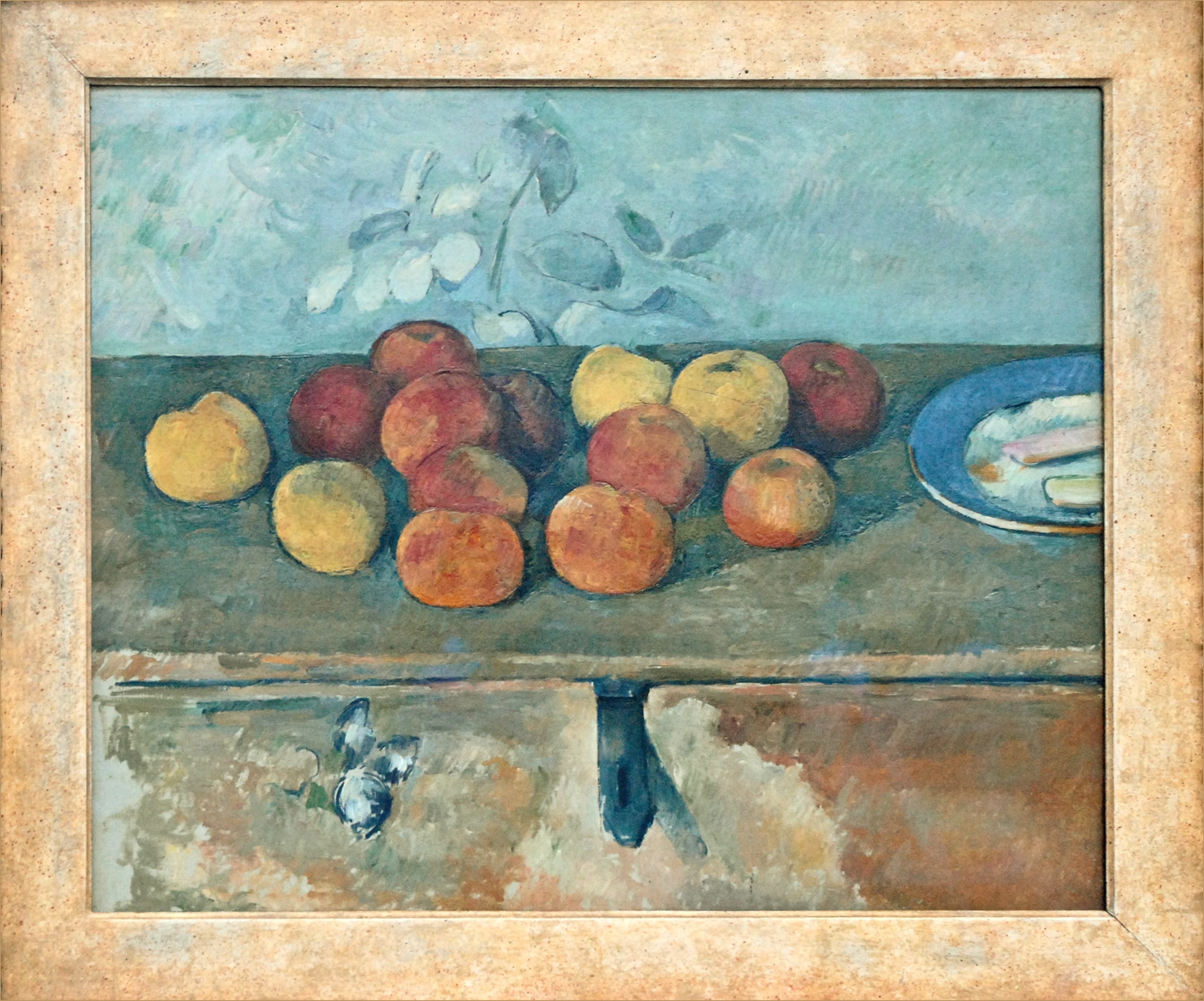 Cézanne's Apples and Biscuits: red and yellow apples on a chest beside a plate of biscuits, against a grey-blue wall