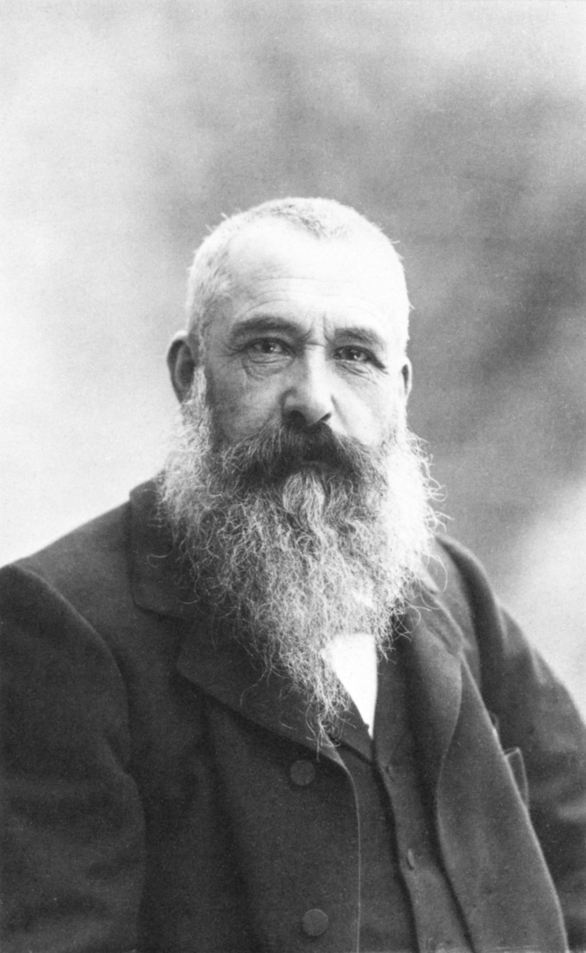 Claude Monet at fifty-nine, white-haired with a full beard, in a dark jacket, looking directly at the camera