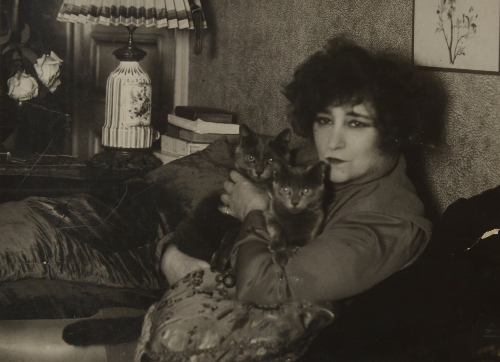 Colette seated indoors with several cats in the 1930s