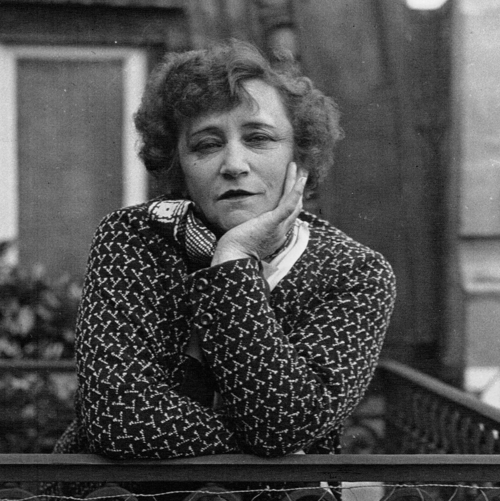 Colette resting her cheek on one hand and looking toward the camera in 1932