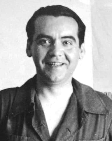 Federico García Lorca smiling in an open-collared shirt at the Huerta de San Vicente.