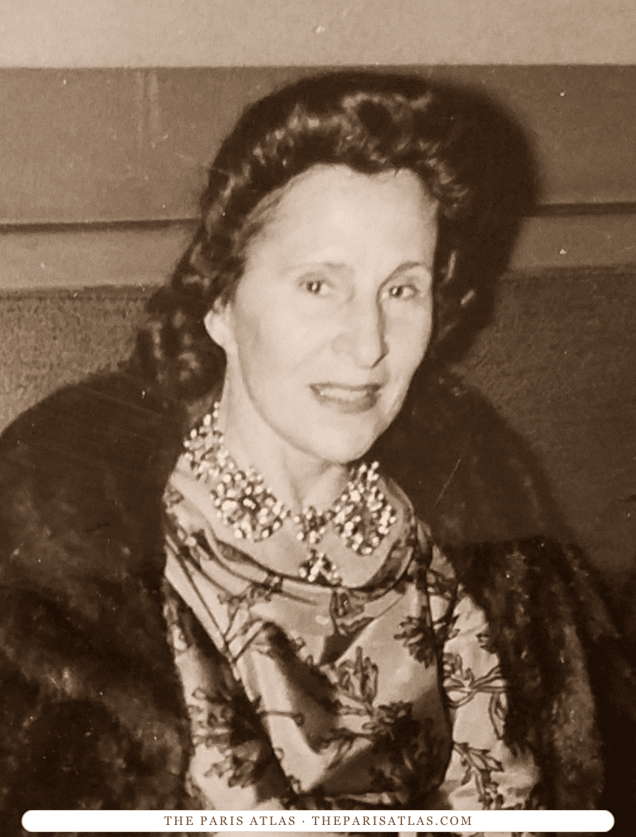 Gala Dalí seated in a patterned dress and dark fur wrap, looking toward the camera