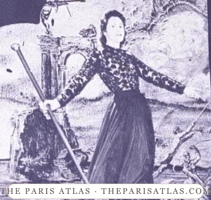 Gala Dalí in a long dark dress with her arms extended, holding a cane in front of an enlarged portrait of Salvador Dalí