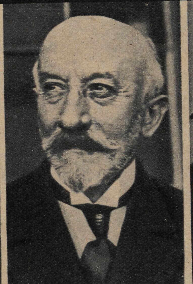 Georges Méliès in old age, white-moustached, in a dark suit, looking at the camera