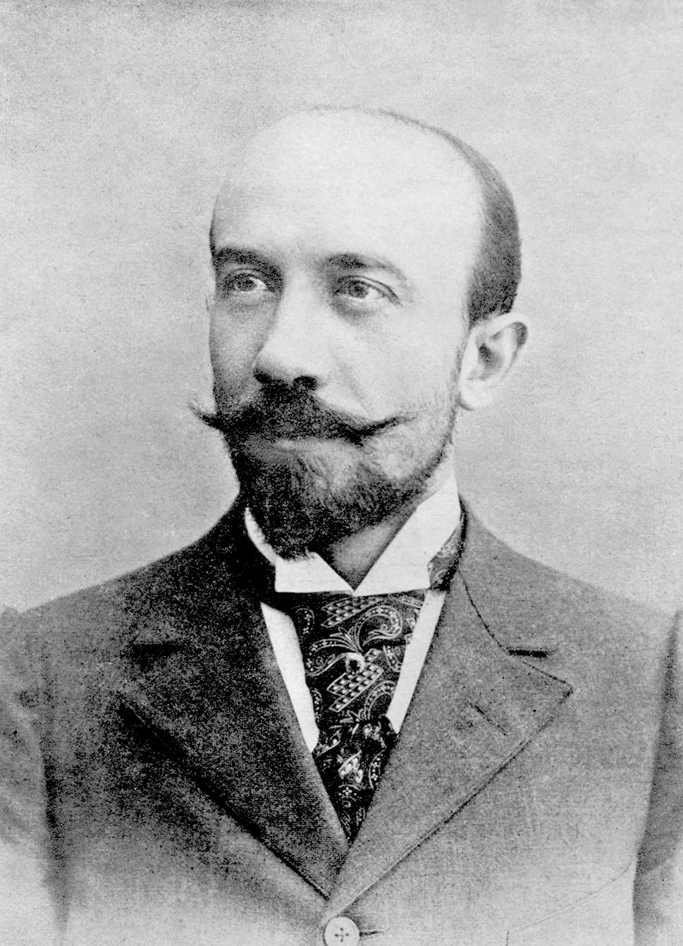 Georges Méliès around 1895: balding, with a waxed mustache and pointed beard, in a suit and paisley cravat