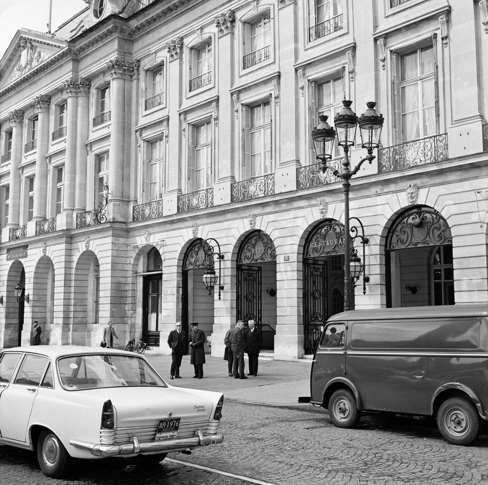 The arcaded Place Vendôme entrance of the Hôtel Ritz in 1965, doorman and guests outside