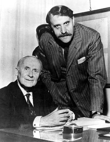 Joan Miró and Carlo Cardazzo standing side by side in suits, Miró on the left with his hands clasped.