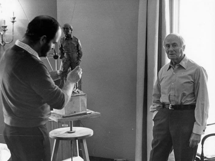 Joan Miró at eighty-five, seated in a jacket and sweater, while the sculptor Joaquim Ros i Sabaté works on a clay bust of him.