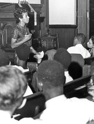Lorraine Hansberry speaking into a microphone before an audience, around 1959
