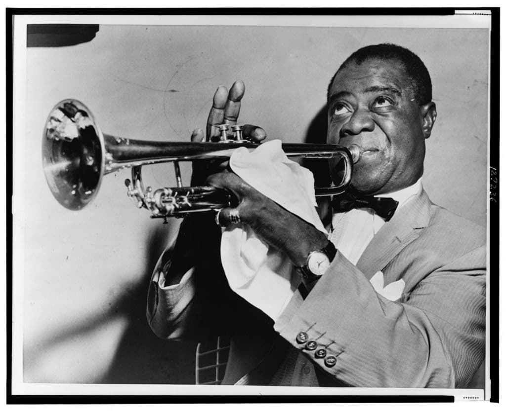Louis Armstrong playing trumpet in 1953, photographed close up in a suit and bow tie
