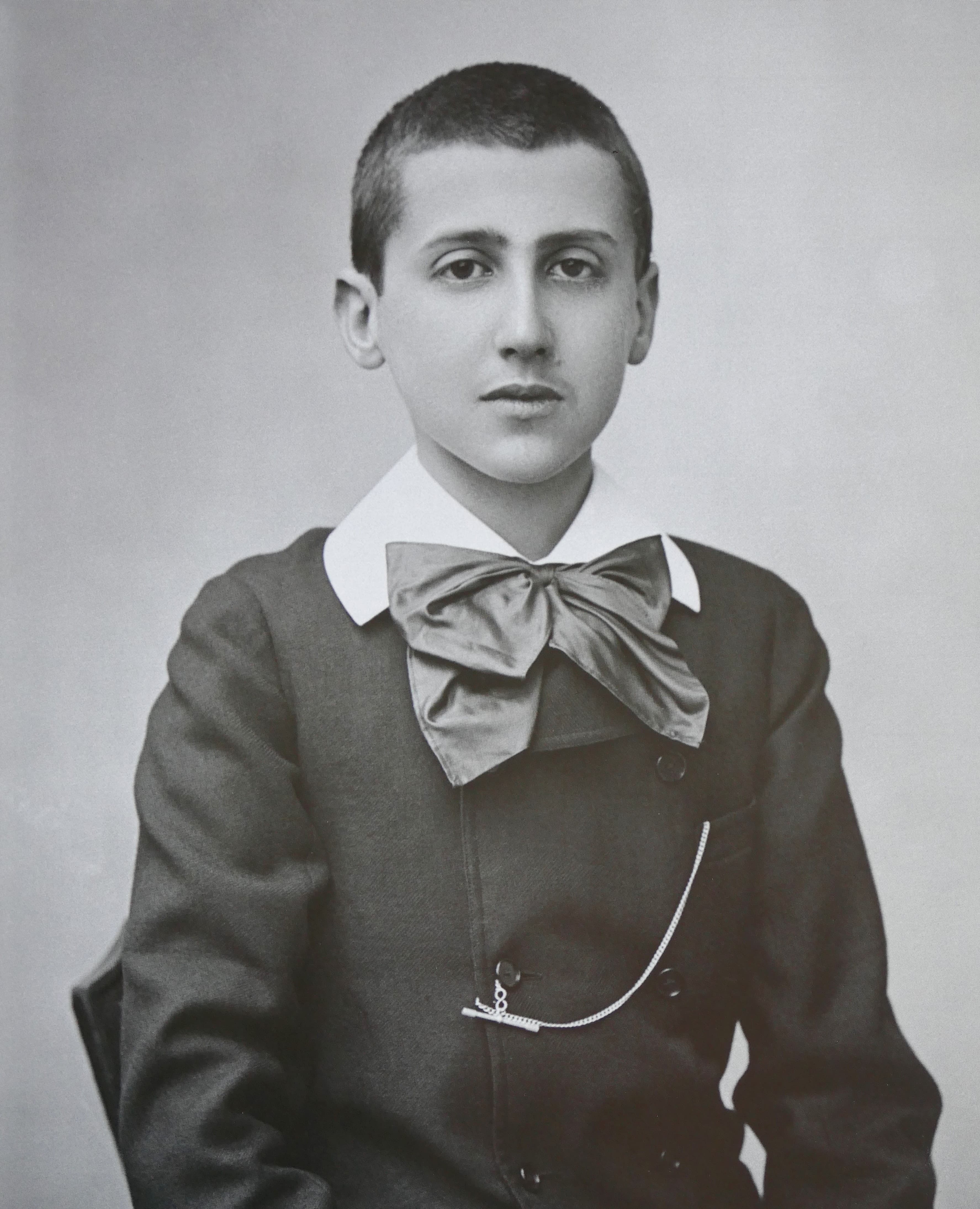 Studio portrait of Marcel Proust at fifteen, in a dark jacket with a large silk bow at the collar.