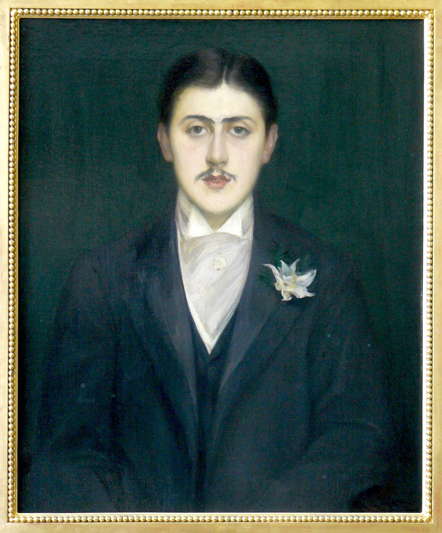 Oil portrait of the young Marcel Proust, pale against a dark background, an orchid at his lapel.