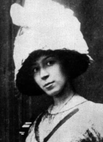 Marie Laurencin around 1912, a young woman in a wide dark hat with a white plume, looking over her shoulder