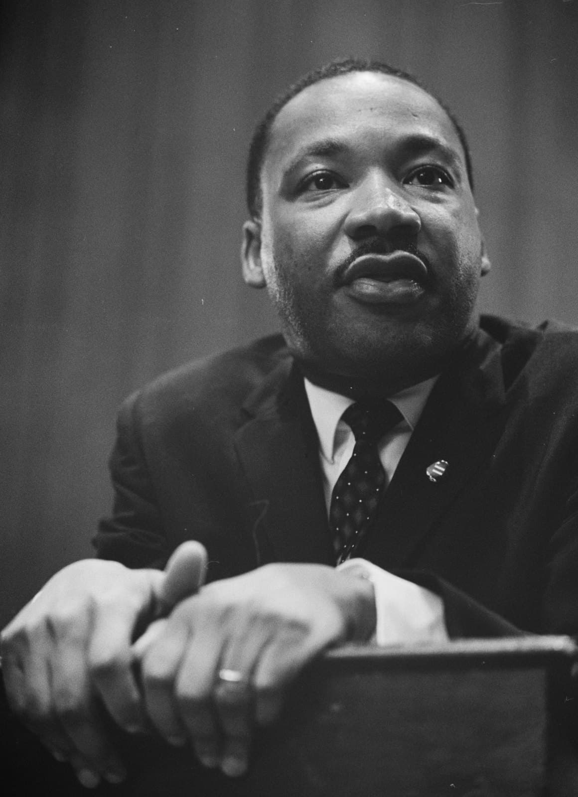 Martin Luther King Jr. leaning forward at a lectern in March 1964, looking just above the camera