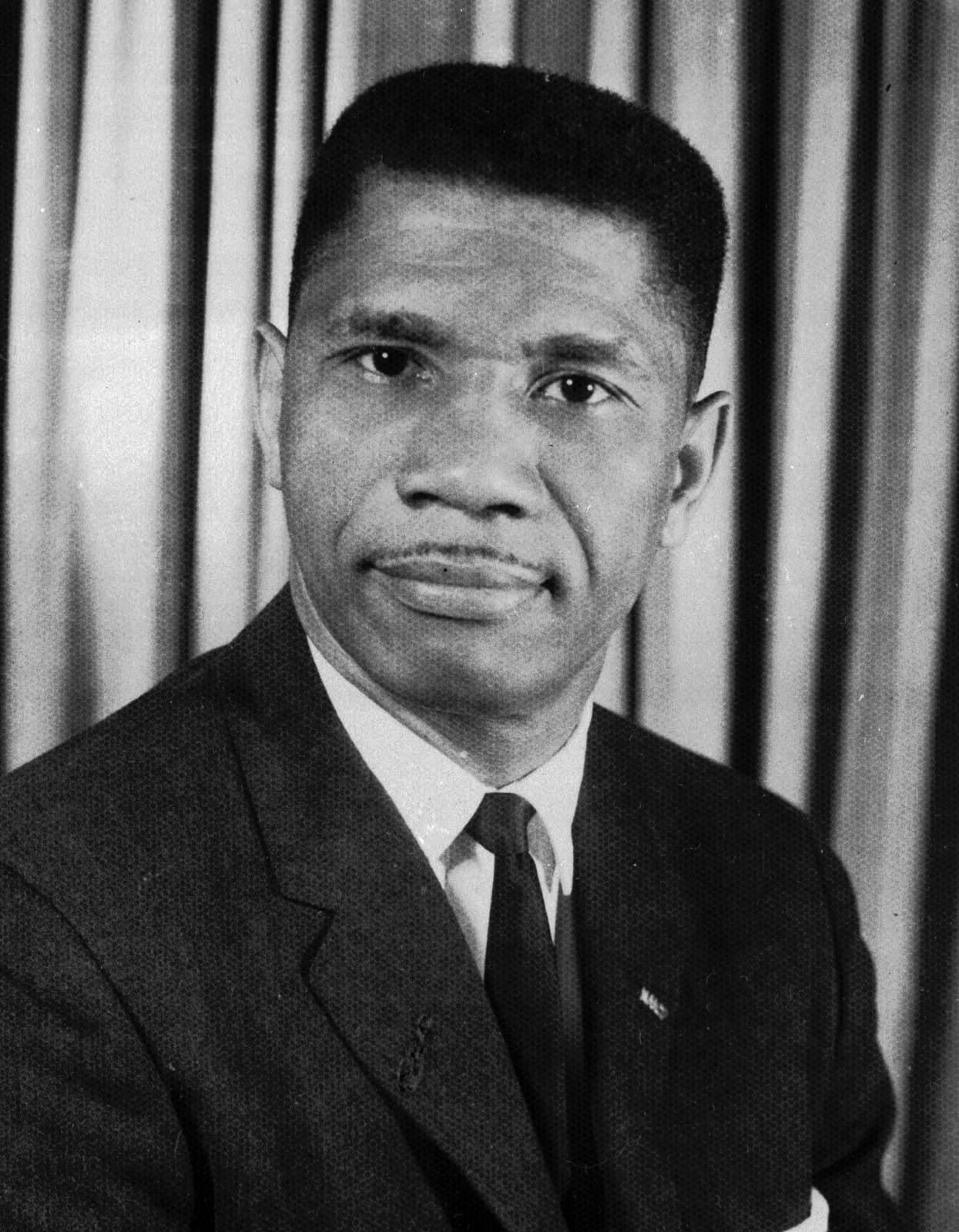 Black-and-white press portrait of civil rights organizer Medgar Evers in a suit and tie.
