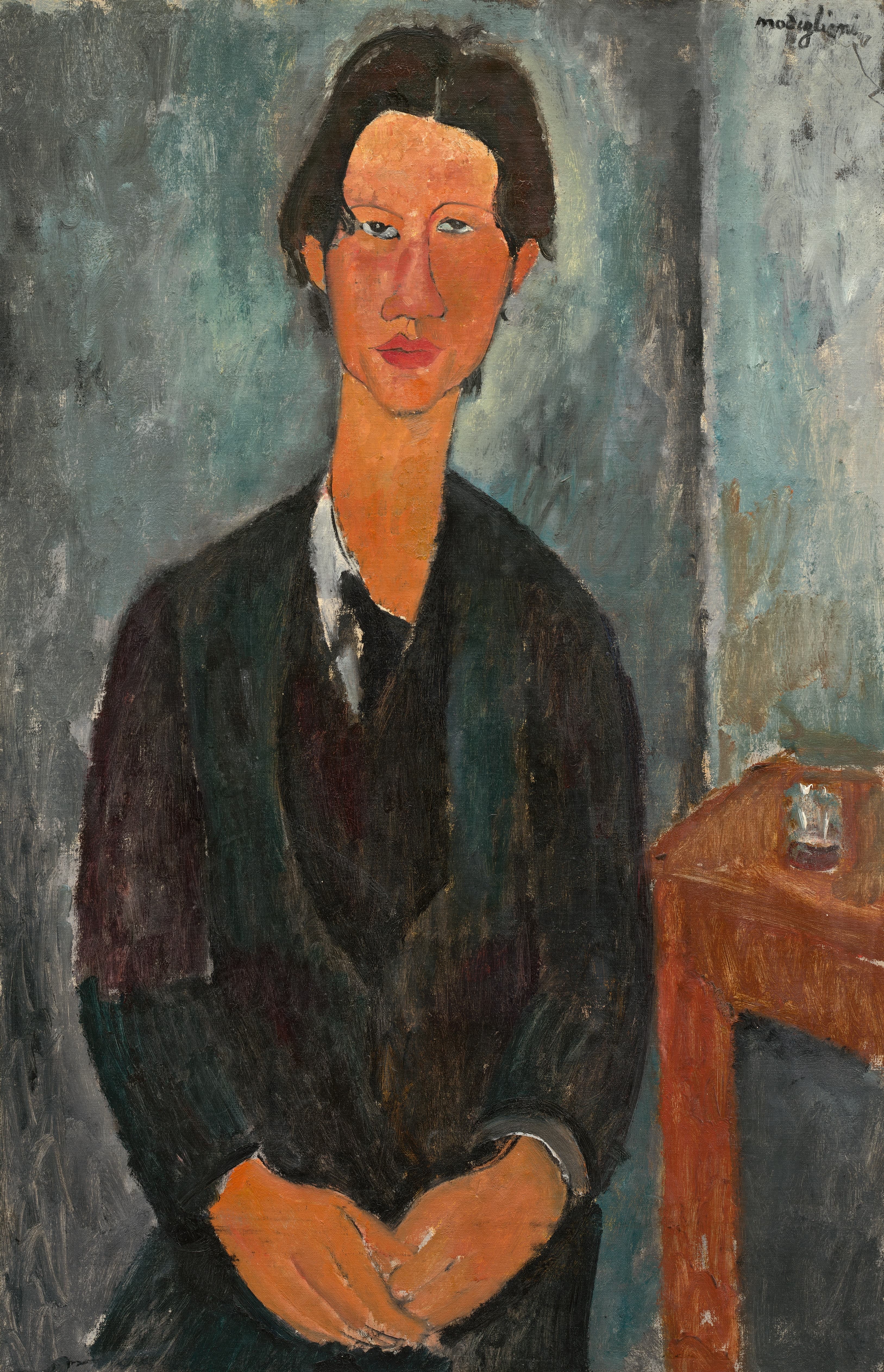 Modigliani's portrait of Soutine seated with hands folded, elongated face and neck, dark jacket over white collar, against a blue-grey ground