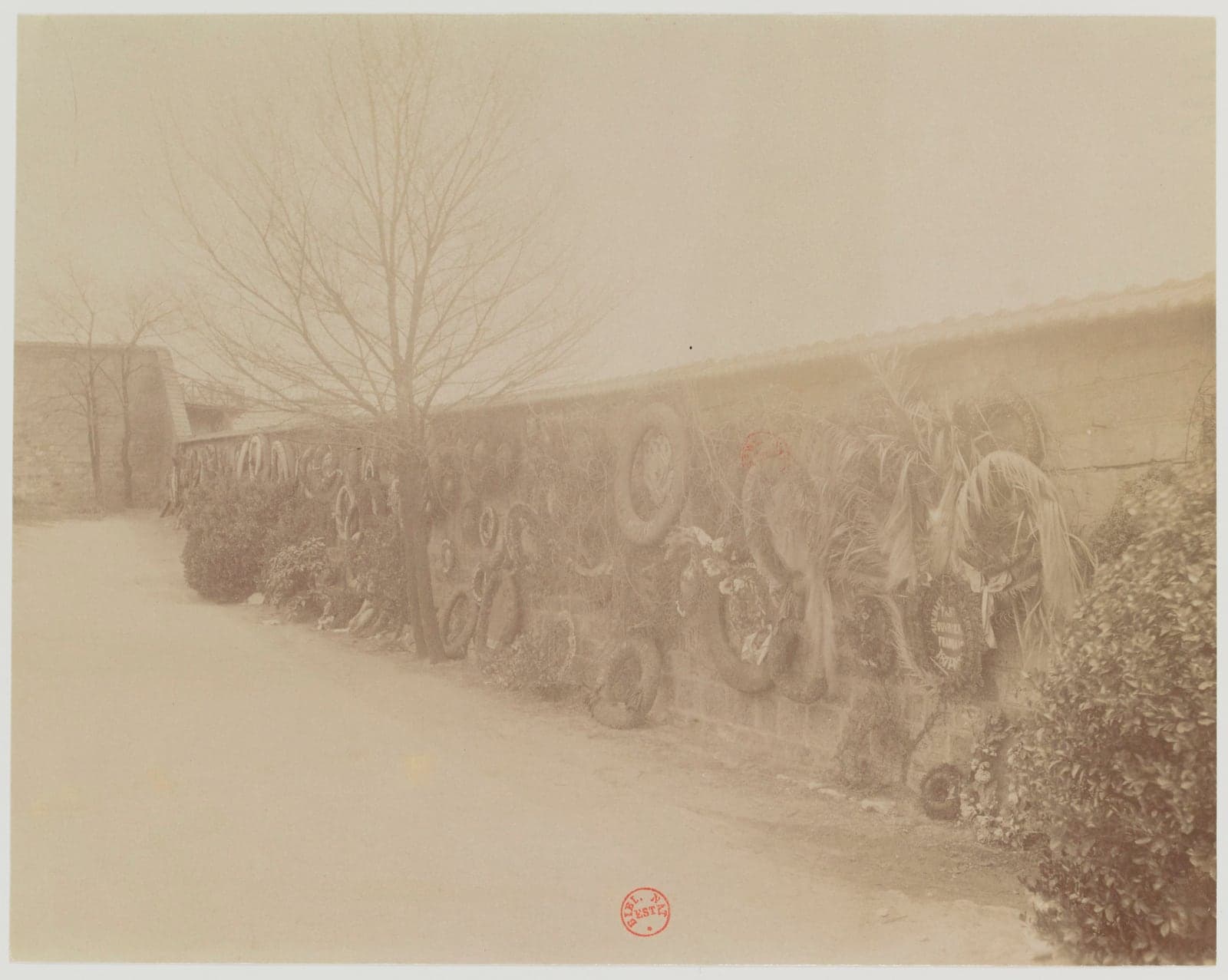 The Mur des Fédérés at Père-Lachaise hung with memorial wreaths, photographed by Eugène Atget in 1900