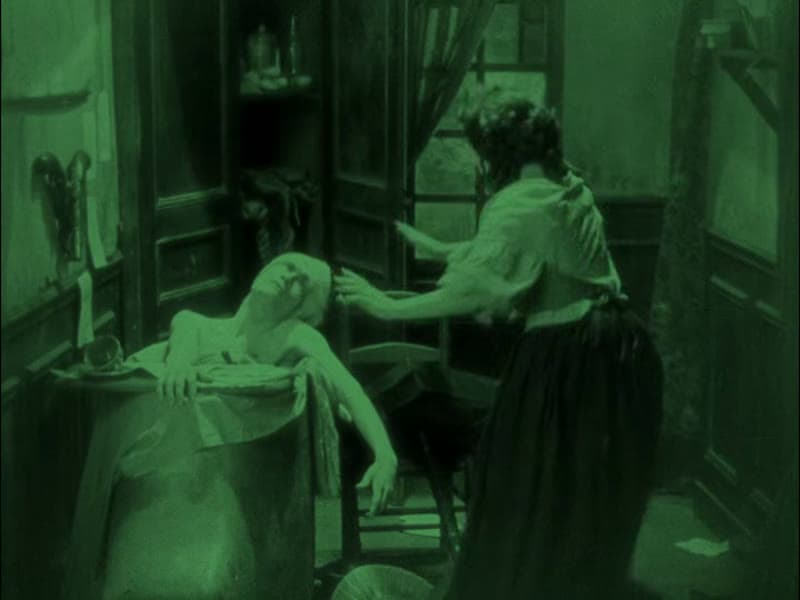 Marat slumped dead over the edge of his bath as Charlotte Corday stands over him, green-tinted