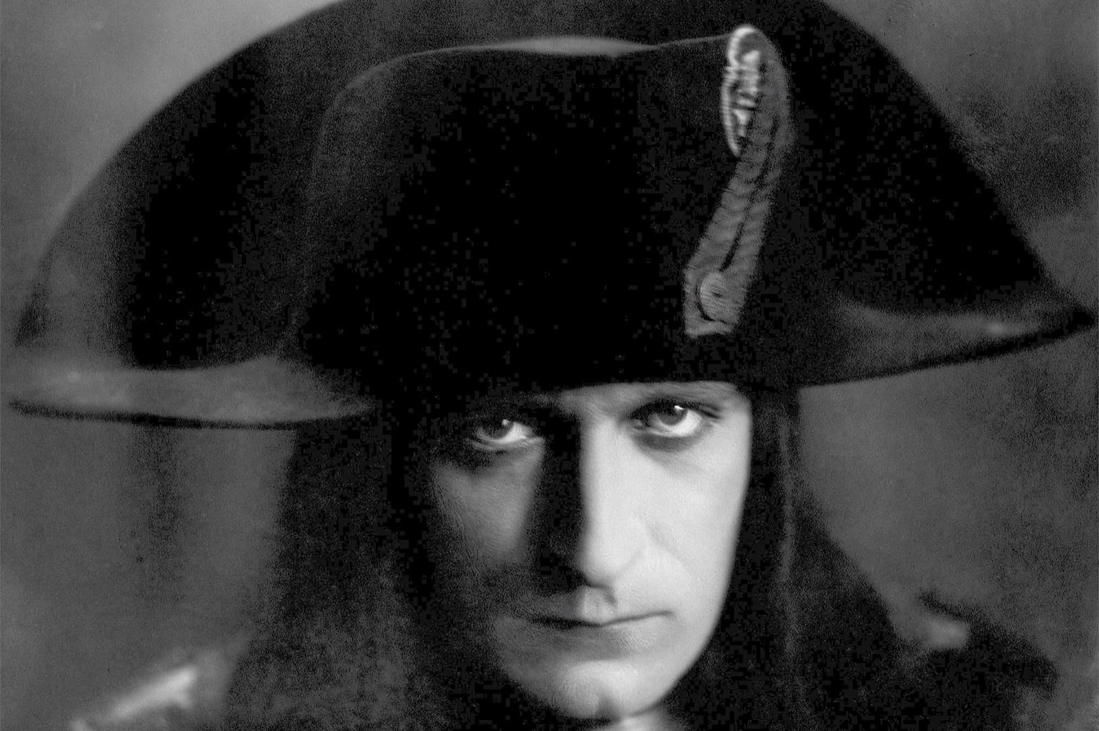 Albert Dieudonné as Napoléon in bicorne hat and long hair, staring directly into the camera in a high-contrast studio portrait