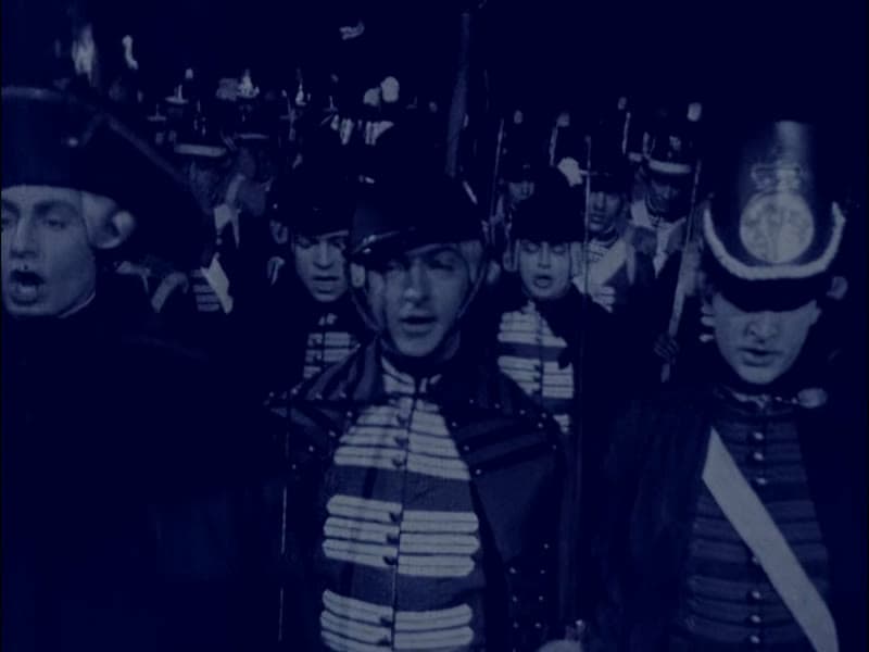Soldiers massed in darkness before the assault on Toulon, faces lit against deep blue night