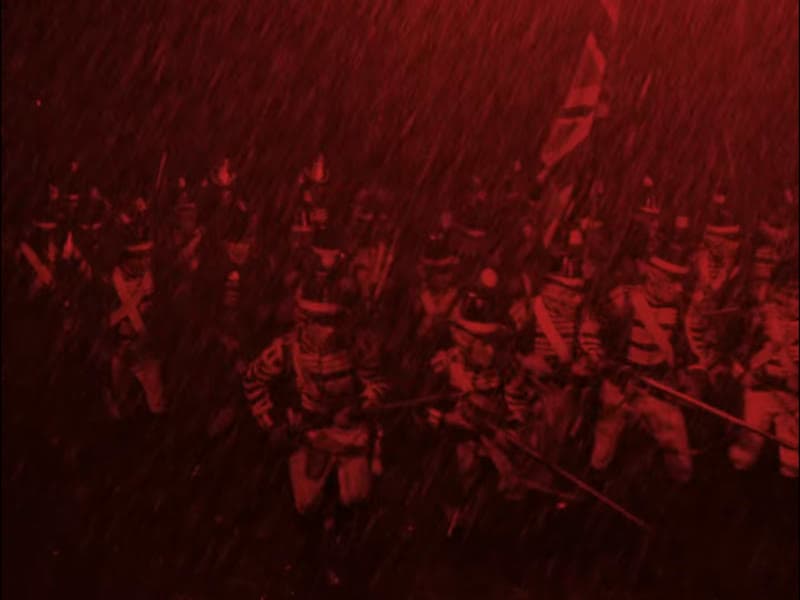 Infantry advancing through torrential rain at night under a battle flag, the whole frame tinted deep red