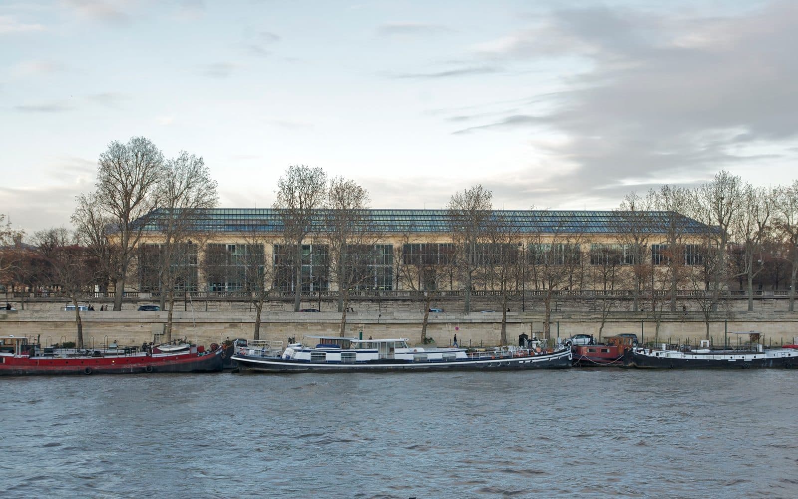 The Orangerie des Tuileries seen from across the Seine, its long glazed roof above the trees of the Terrasse du Bord-de-l'Eau