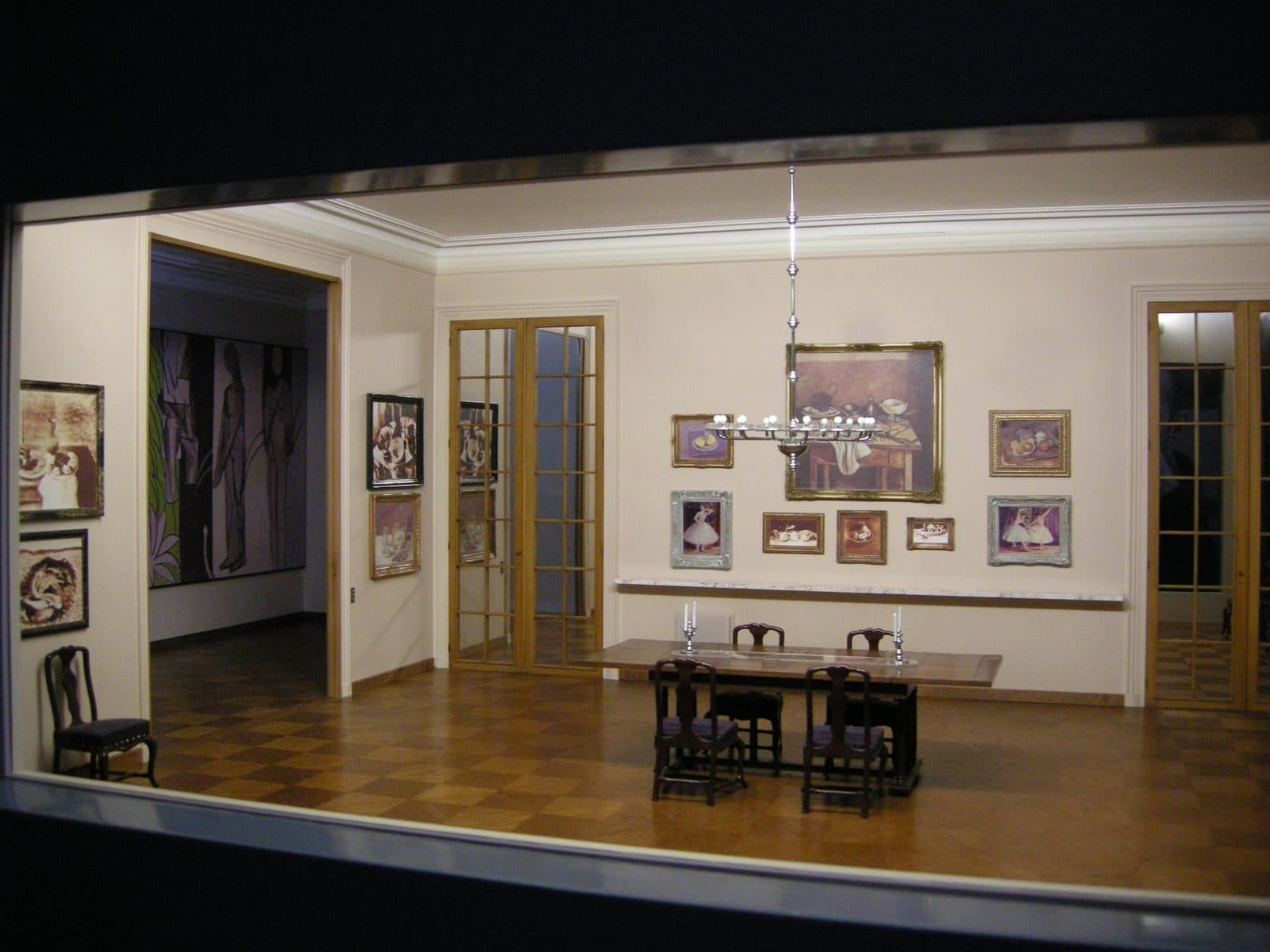 Scale-model room seen through a viewing window at the Musée de l'Orangerie, miniature paintings hung over a dining table and parquet floor