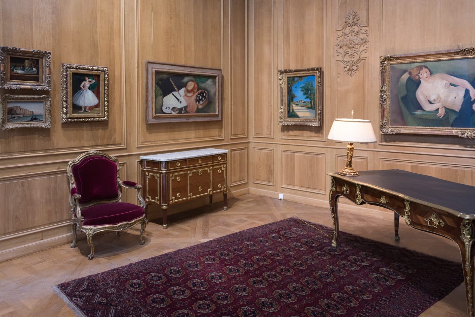 Wood-panelled salon at the Musée de l'Orangerie hung with paintings and furnished with a desk, commode, and velvet armchair