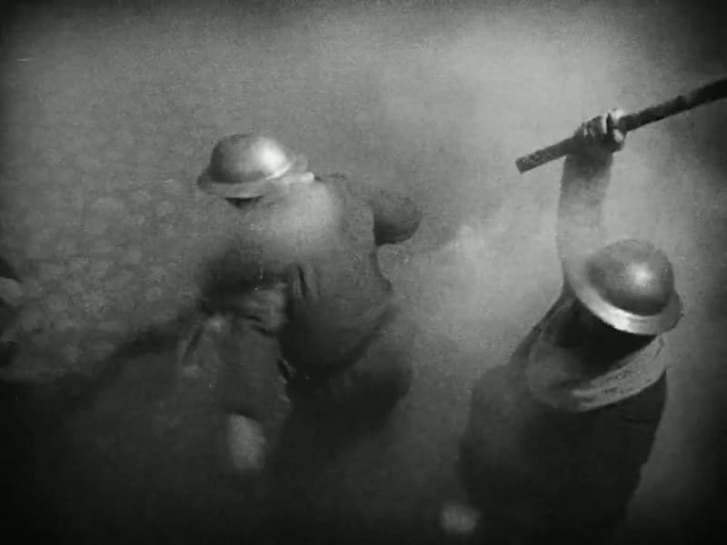 Helmeted soldiers swing weapons at the crowd, seen from above through smoke