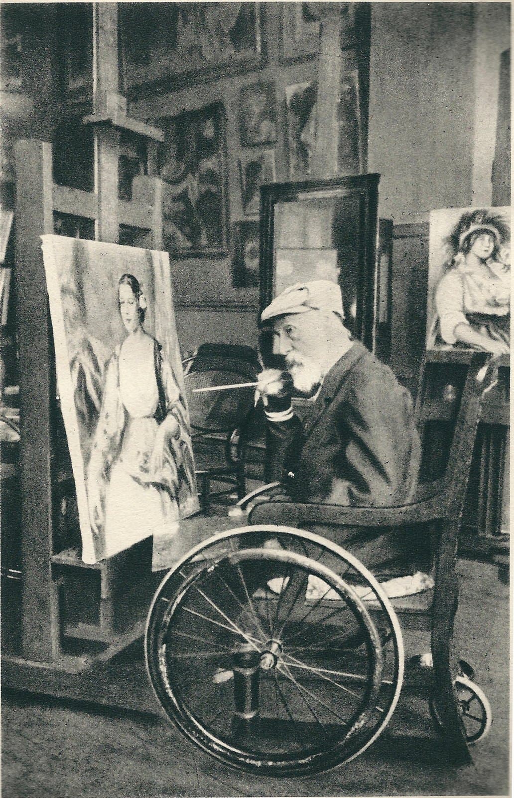 The elderly Renoir seated at an easel in his studio, a brush in his visibly deformed hand, a canvas of figures before him