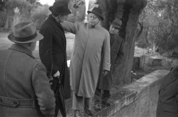 Jean Renoir standing outdoors at Villa Adriana with Carl Koch and Luchino Visconti during location scouting