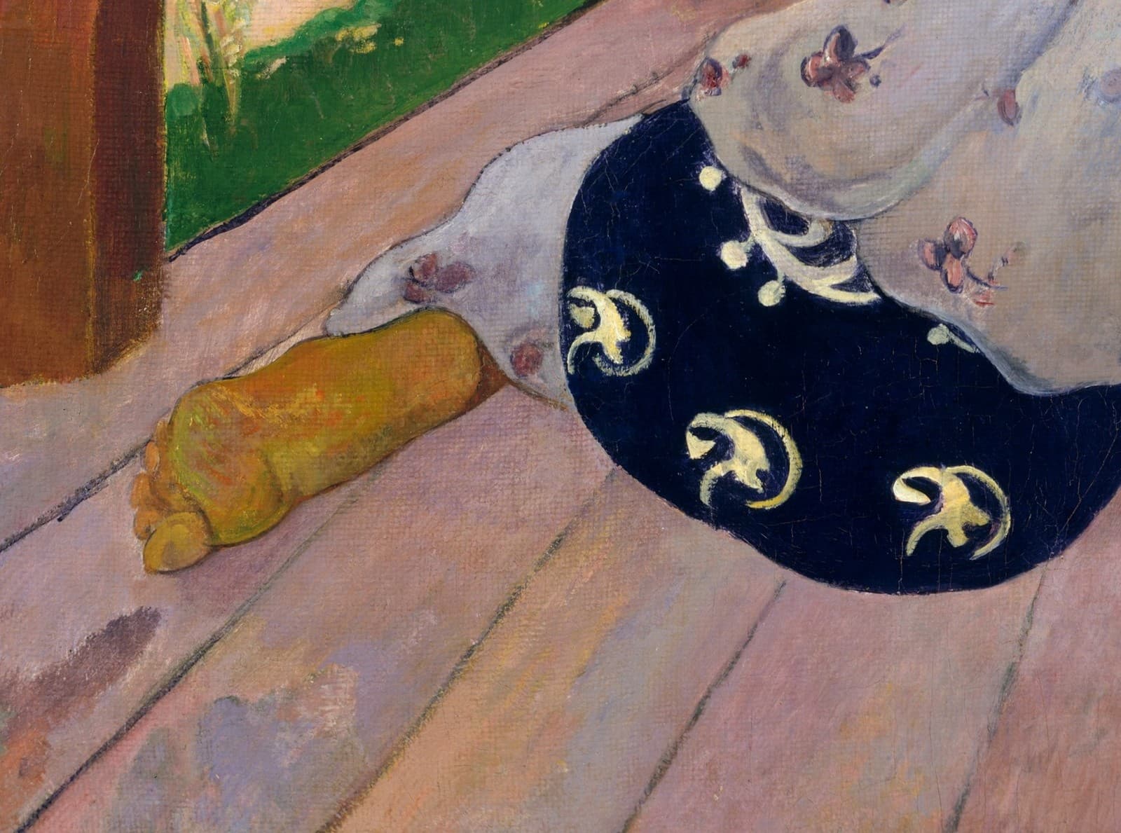 Detail of The Siesta: a bare foot with a yellow sole tucked beneath a white pareu printed with flowers, on pink deck boards