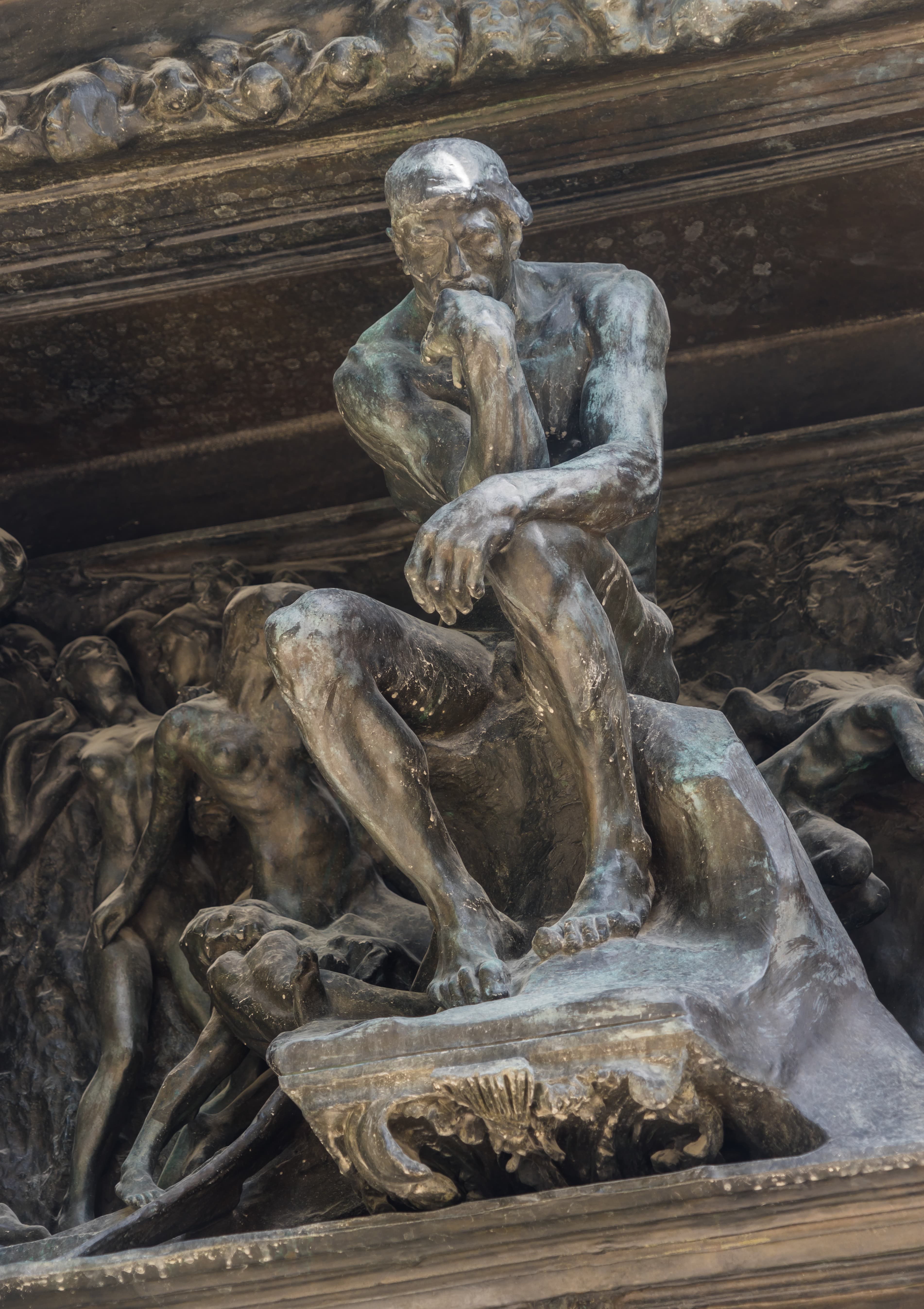Auguste Rodin's small Thinker seated above the crowded figures at the top of the bronze Gates of Hell in the Musée Rodin garden