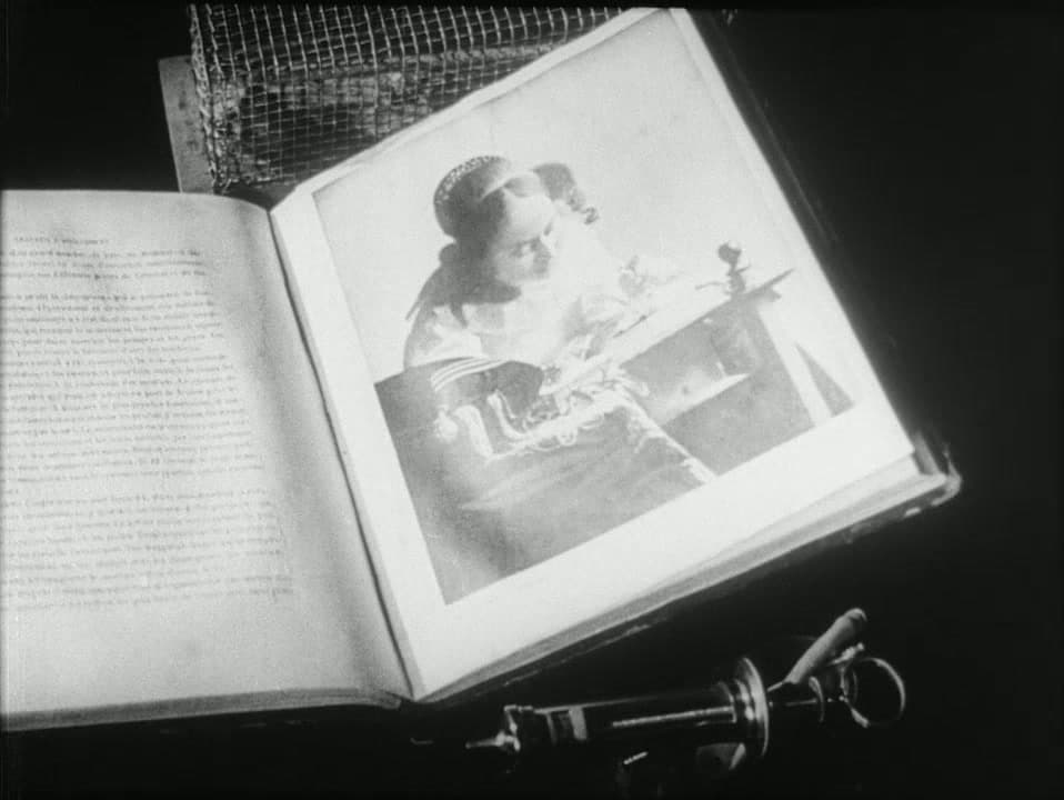 A book lies open to a reproduction of Vermeer's The Lacemaker in Un Chien Andalou